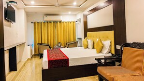 A hotel room with a bed, a TV, a desk, a chair, and a ceiling fan. - Shanti Bhawan Heritage Hotel (Jodhpur)