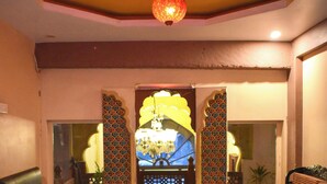 A lobby with a chandelier, a sofa, a bench, and a decorative gate. - Shanti Bhawan Heritage Hotel (Jodhpur)