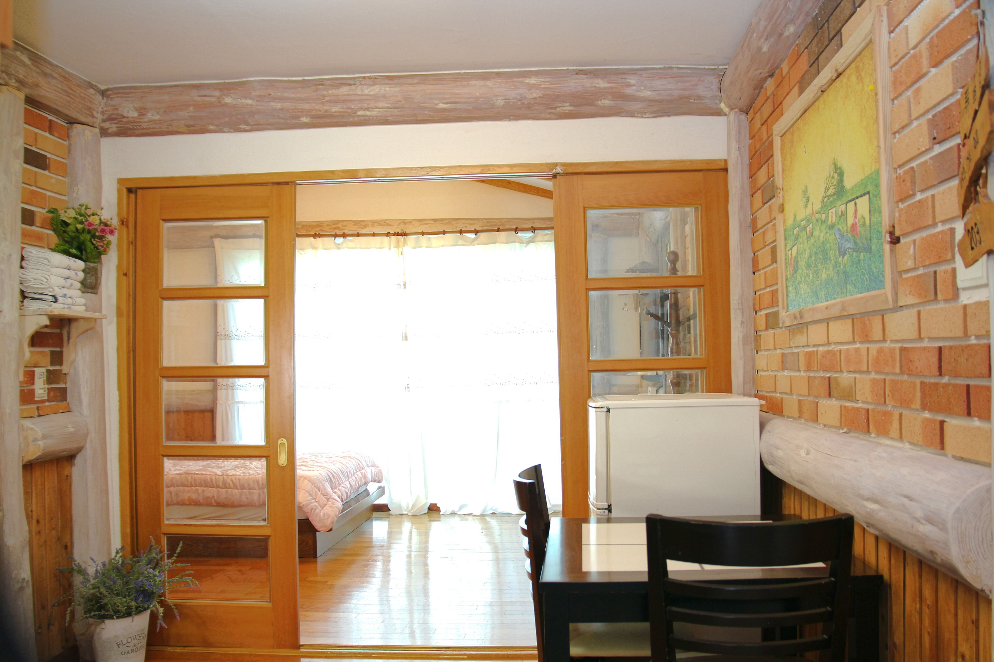 Une pièce comprenant un lit, une table avec des chaises, un radiateur et une fenêtre avec des rideaux.