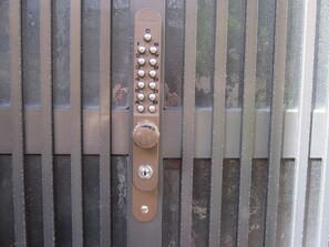Cerradura electrónica con teclado sobre una superficie metálica con barras verticales.