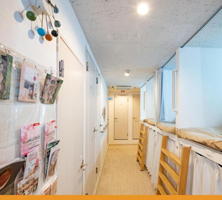 A corridor with bunk beds, a bulletin board with photos, and a door at the end.