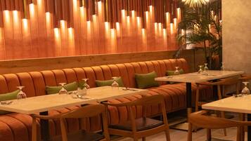 Un interior de restaurante con cabinas de madera, mesas y lámparas modernas.