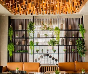 A modern interior with a sofa, a table, and a wall-mounted plant shelf. - Ironwood Hotel (Tacloban)