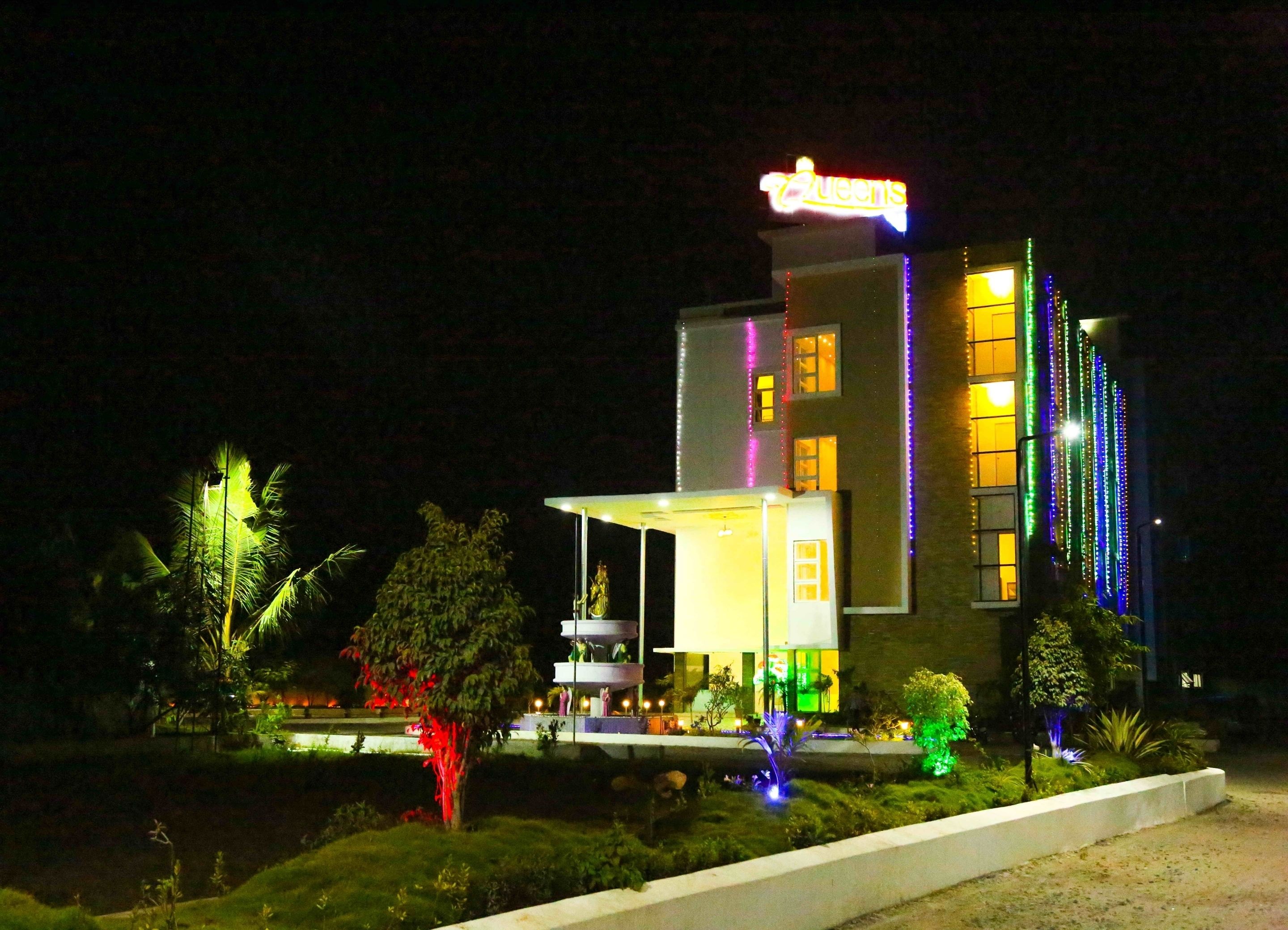 Un hotel de diseño moderno, con un llamativo letrero de neón, múltiples ventanas iluminadas y una zona de entrada bien iluminada.
