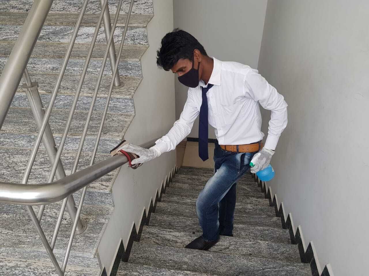 Una persona pulisce una scala con uno spruzzino e un panno.