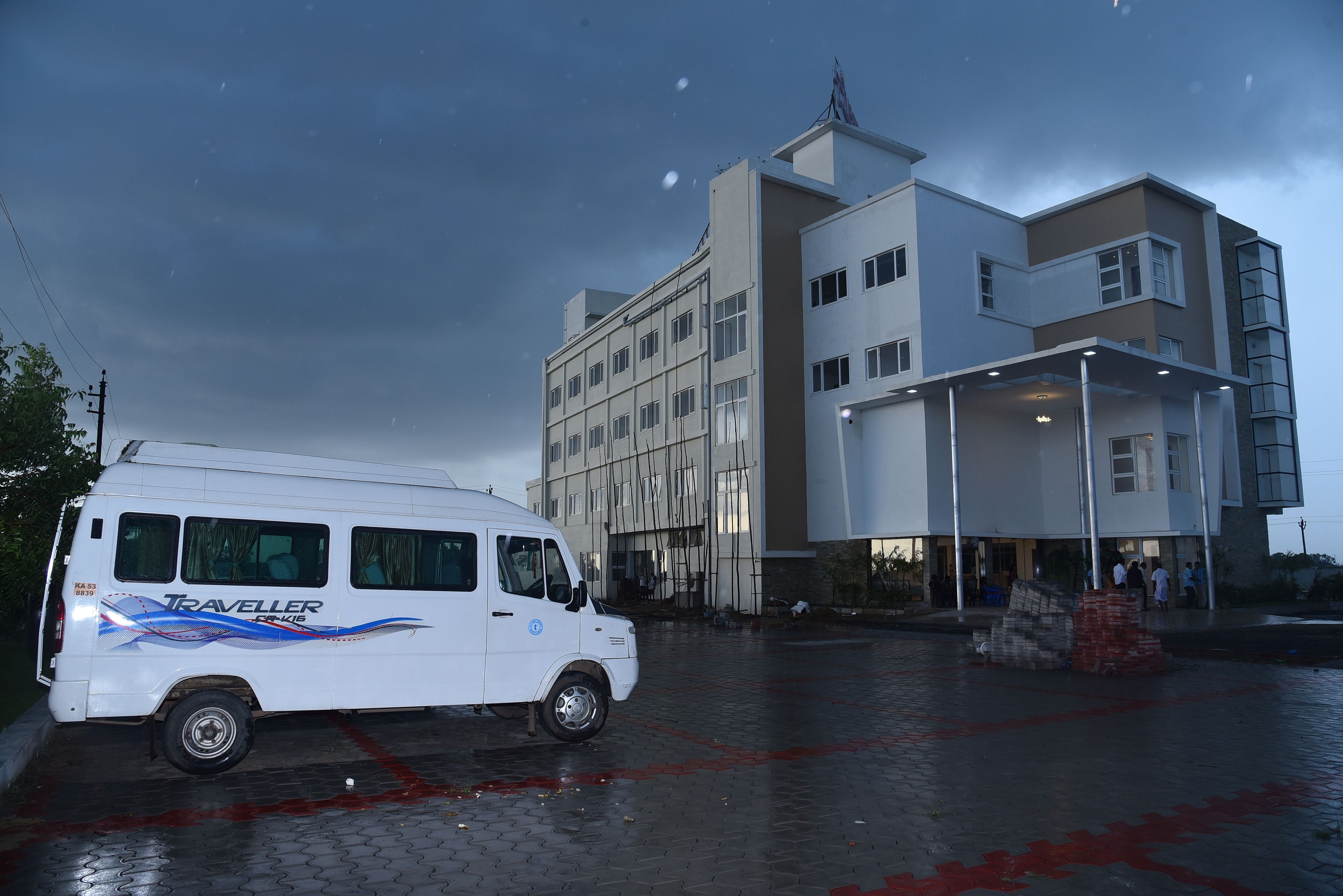 A white van parked in front of a modern building with multiple floors and a covered entrance.