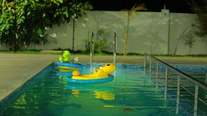 A swimming pool with inflatable rings and a metal railing. - Queens Inn (Velankanni)