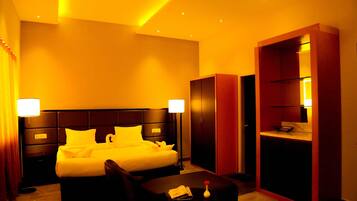 Une chambre d’hôtel avec un grand lit, un bureau, une chaise, une armoire et un miroir.