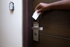 A hand inserting a card into a modern door lock. - Grande Inn (Tiruchirappalli)