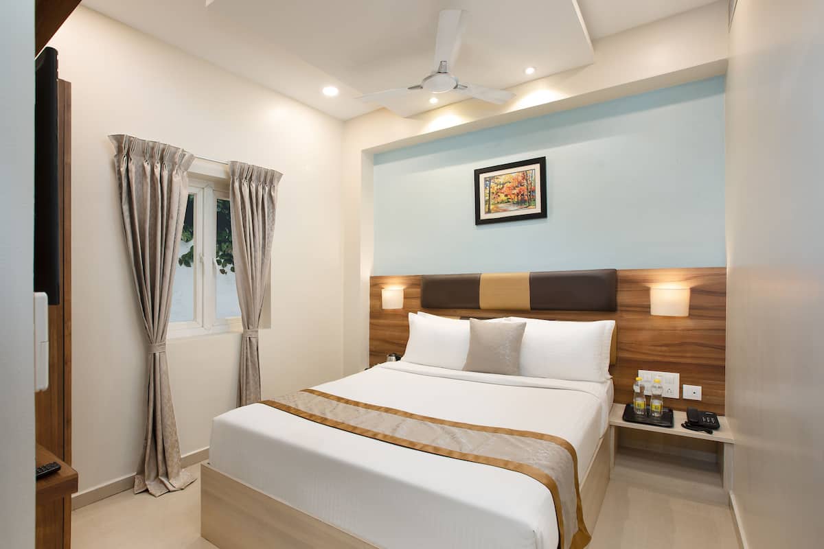 A neatly arranged hotel room with a bed, bedside table, and a wall-mounted light fixture.