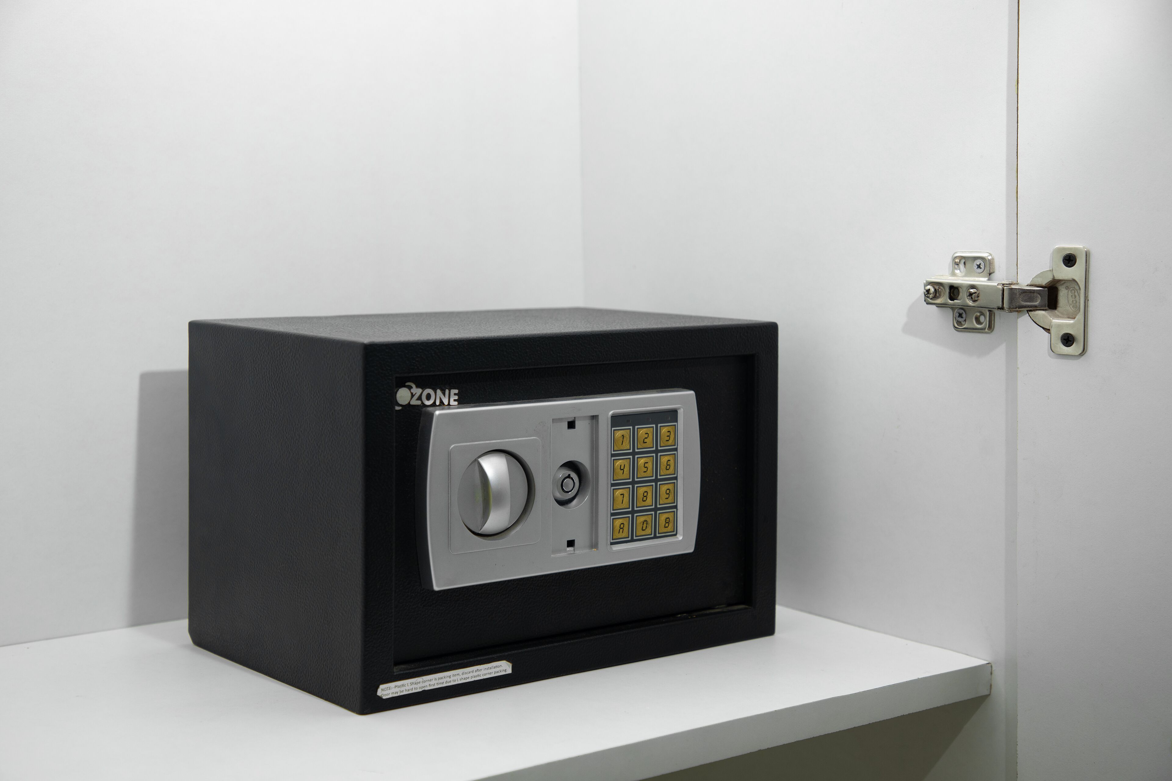 A black safe with a numeric keypad and a lock mechanism, mounted on a white wall.