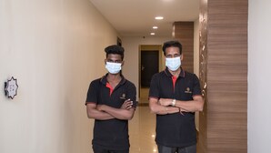 Dois homens em um corredor, com uma placa na parede identificada como 'F2'.