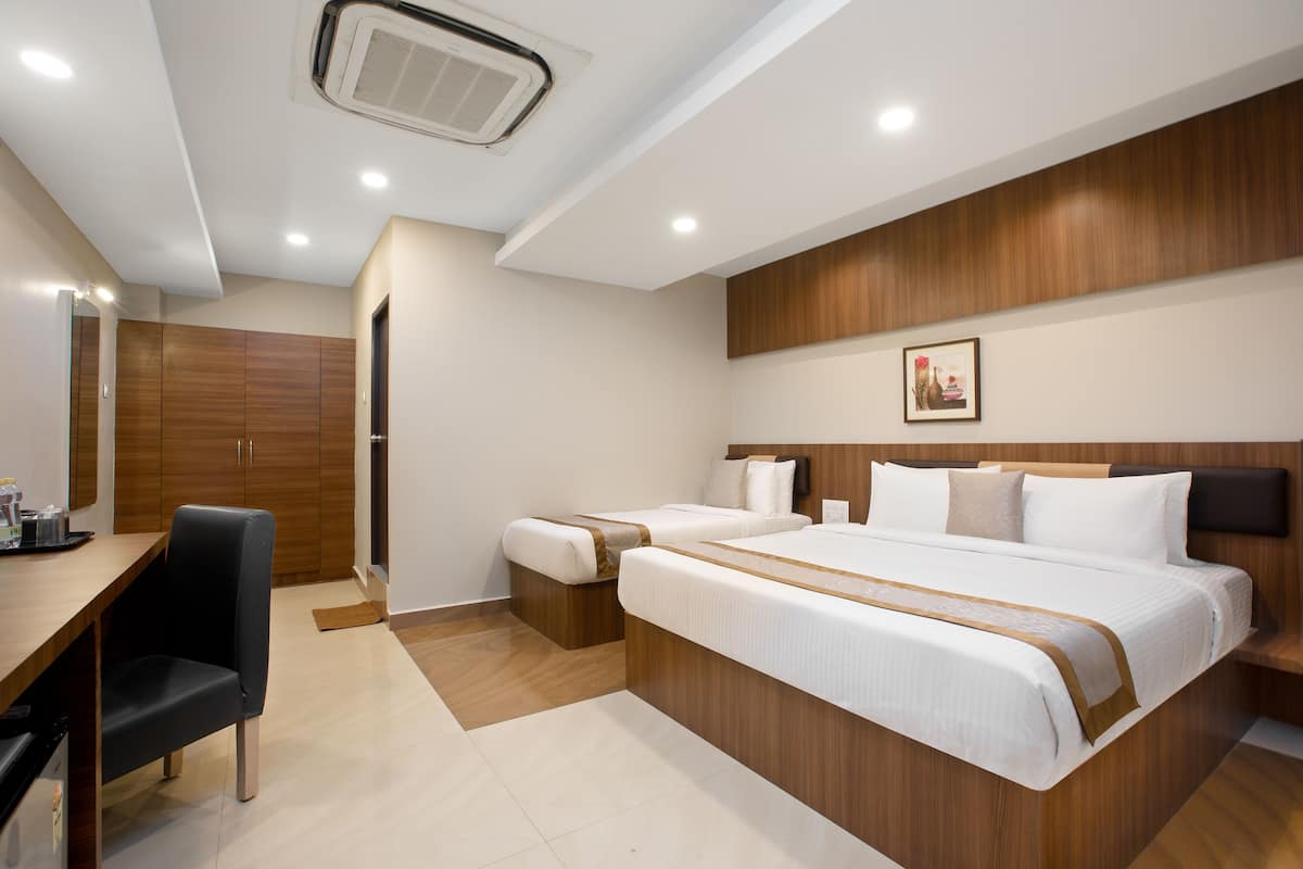 A modern hotel room with a wooden headboard, two beds, a desk, and a chair.