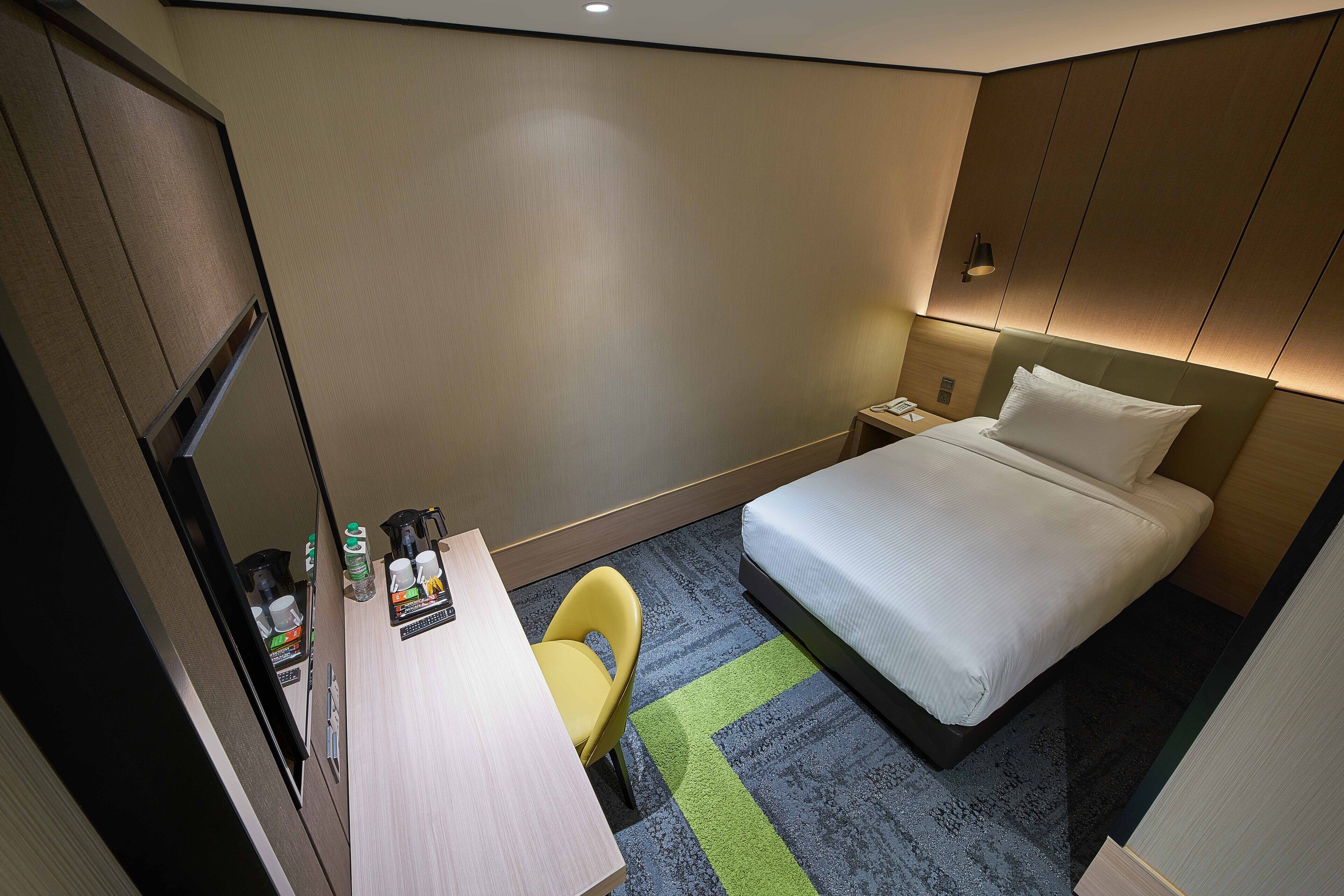 Een hotelkamer met een bed, bureau, stoel en nachtkastje.