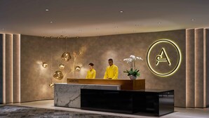 A modern hotel reception area with a marble counter, a large illuminated 'A' logo, and a reception desk. - Aerotel Kuala Lumpur (Sepang)
