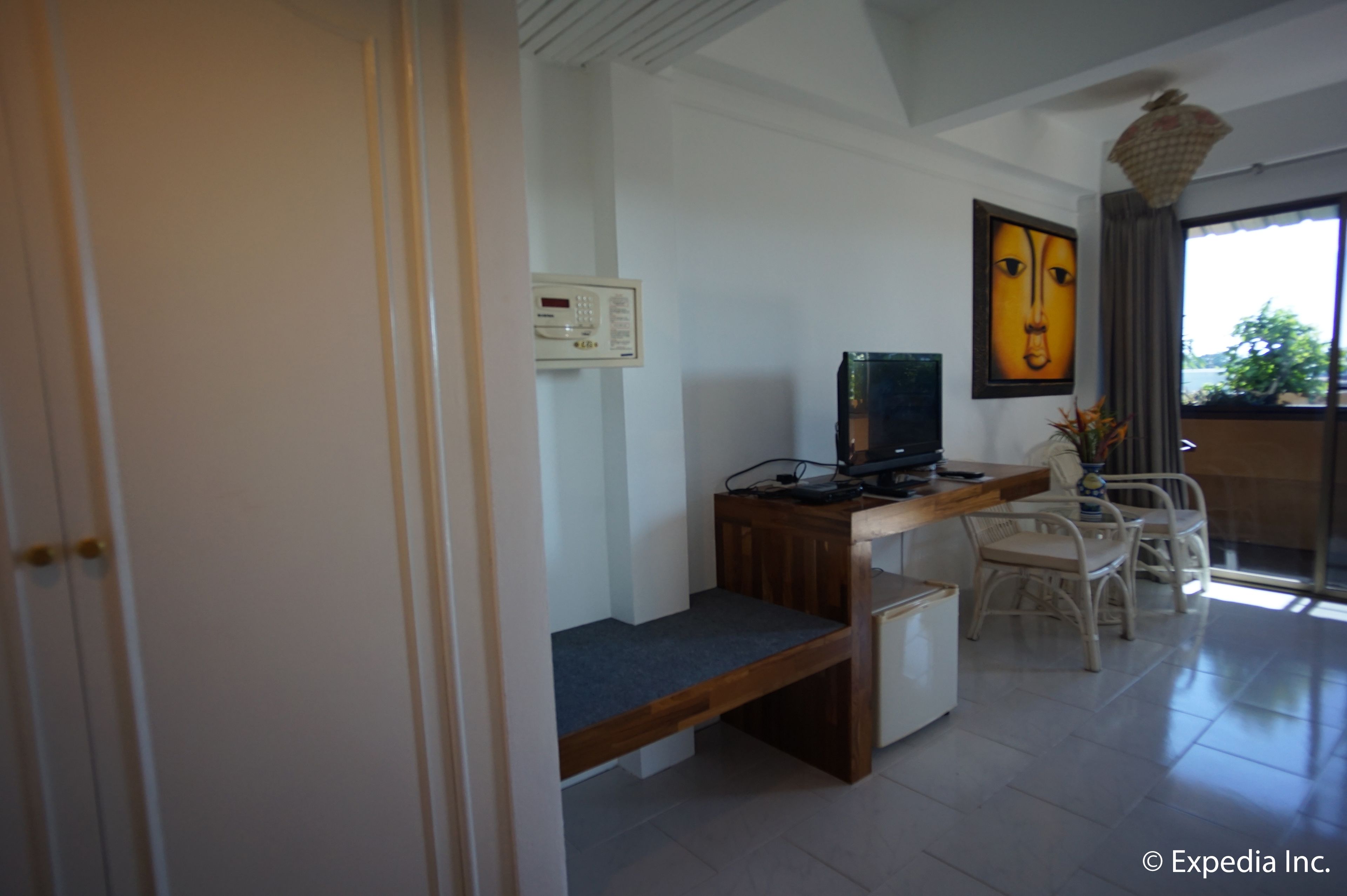 A room with a desk, computer, and two wicker chairs.