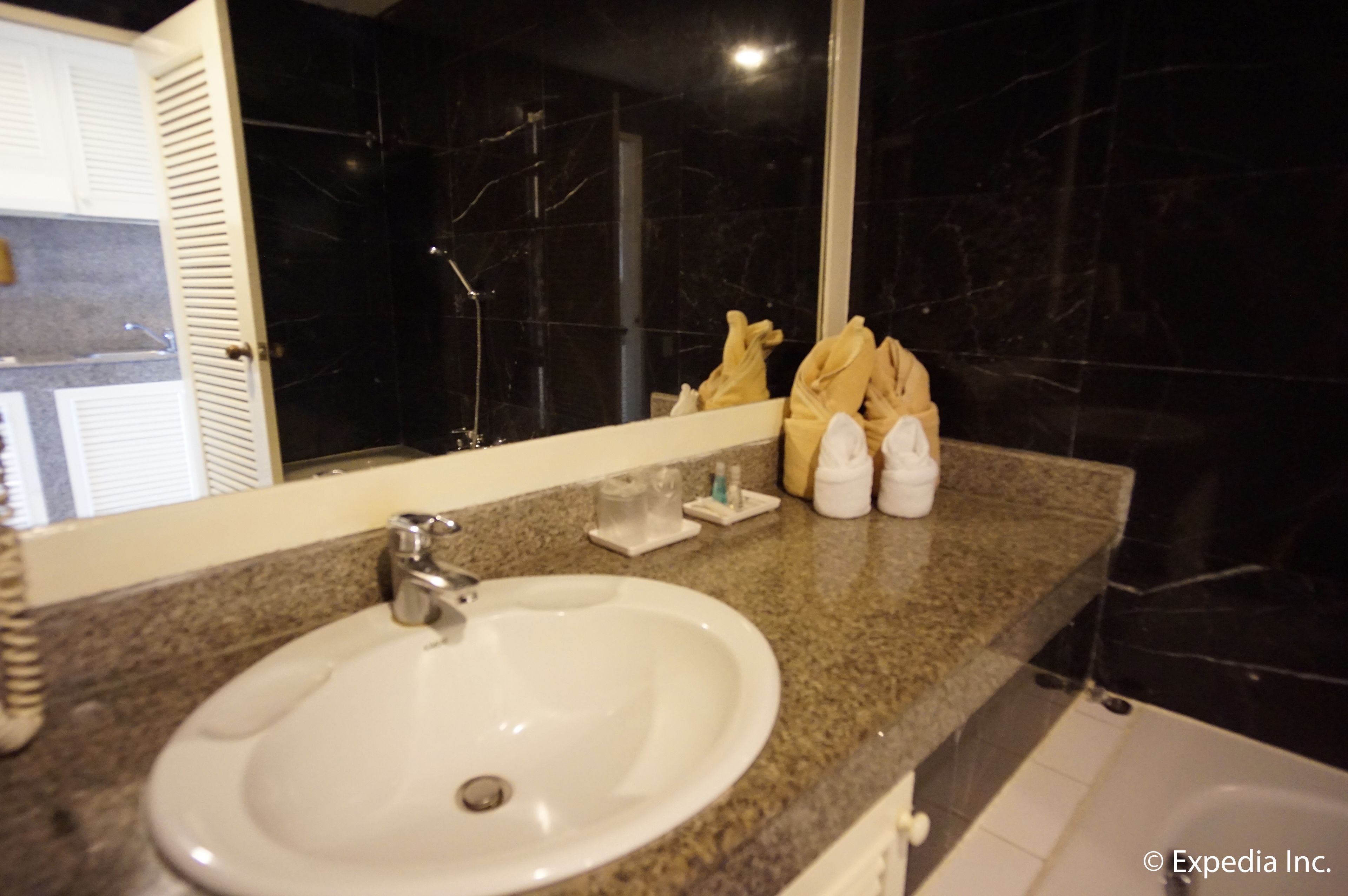 A bathroom with a white sink, a mirror, and a dark marble wall.