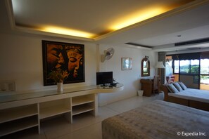 A modern bedroom with a large bed, a desk with a computer, a TV, and a large framed artwork on the wall. - Bougainvillea Terrace House (Karon)