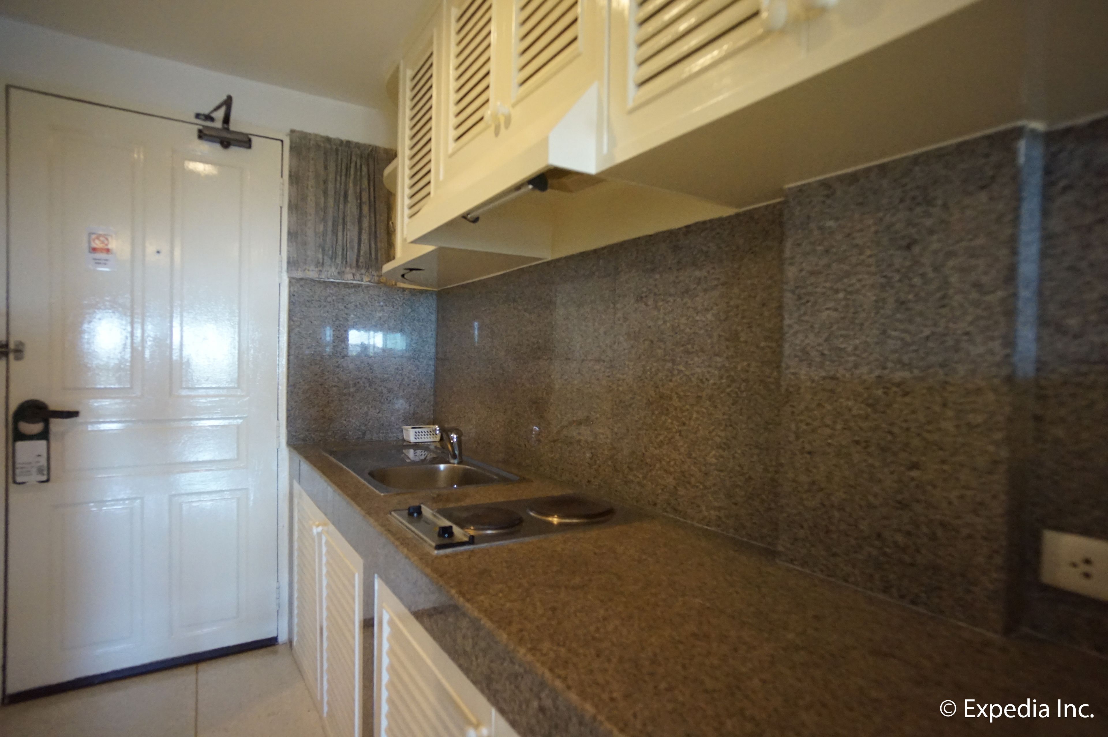 A kitchen with granite countertops, a stainless steel sink, and a white door.