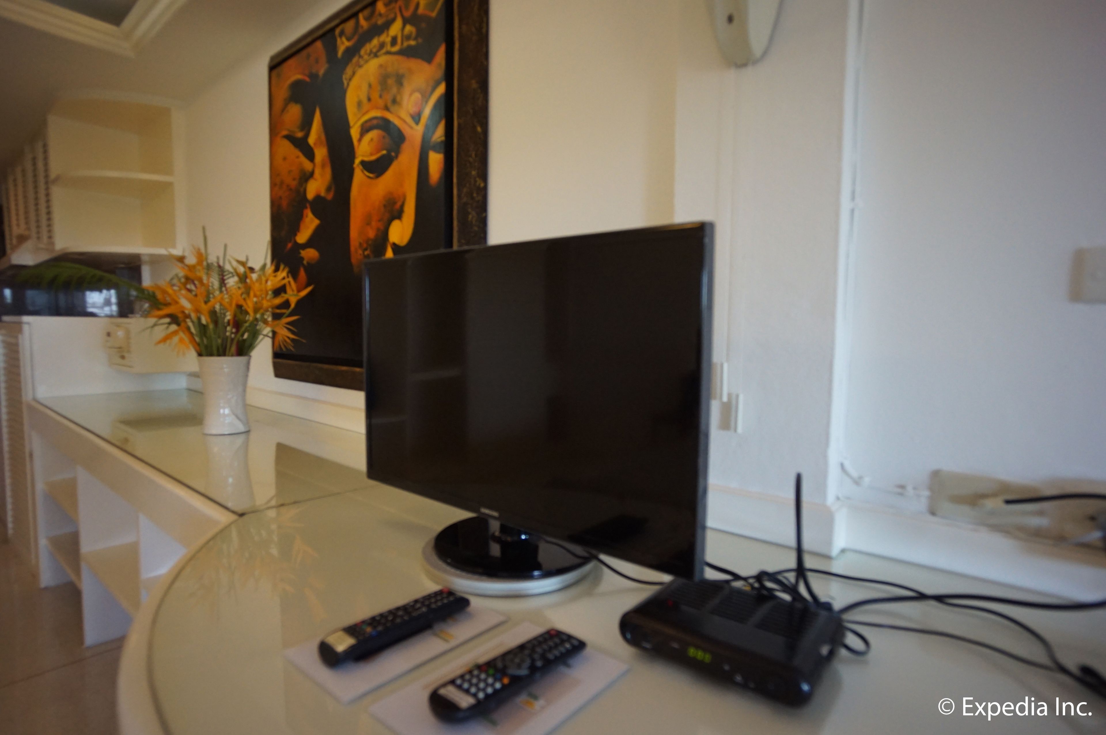 Ein modernes Wohnzimmer mit Flachbildfernseher, Glastisch und einer Topfpflanze.