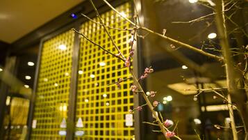 A building facade with a grid-like pattern of windows and a branch with pink blossoms in the foreground.