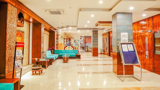 Un vestíbulo de hotel con una recepción, zona de estar y un cartel.