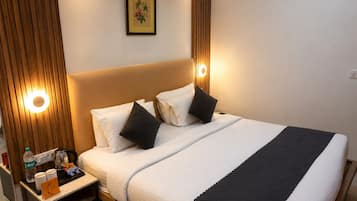 Quarto de hotel com cama, mesa de cabeceira e um quadro na parede.