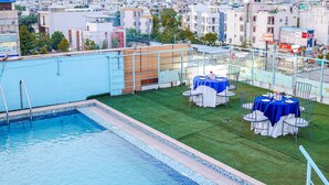 Una piscina en la azotea con vistas al paisaje urbano, que incluye edificios y un letrero que dice 'LIMANO'S CAFE'.