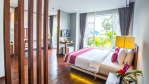 Une chambre d’hôtel équipée d’un lit, d’un bureau, d’une télévision et d’une fenêtre donnant sur un paysage verdoyant.