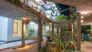 Un jardin intérieur agrémenté de plantes suspendues, de structures en bambou et d’un chemin en briques.
