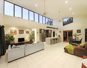 A spacious living area with a large sofa, a dining table, and a kitchen area with a bar.