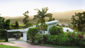 A modern house with a paved driveway and a view of the countryside. - Hilltop Views (Cannonvale)