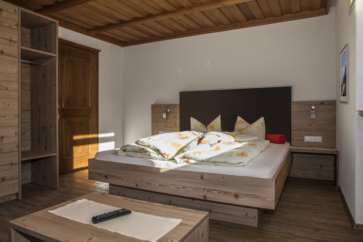 A bedroom with a wooden bed, a nightstand, and a wooden wardrobe.