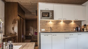 A modern kitchen with white cabinets, a built-in microwave, and a wooden countertop. - Apart Bergland (Kaunertal)