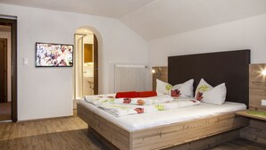 A bedroom with a wooden bed, white bedding, and a wooden headboard. - Apart Bergland (Kaunertal)