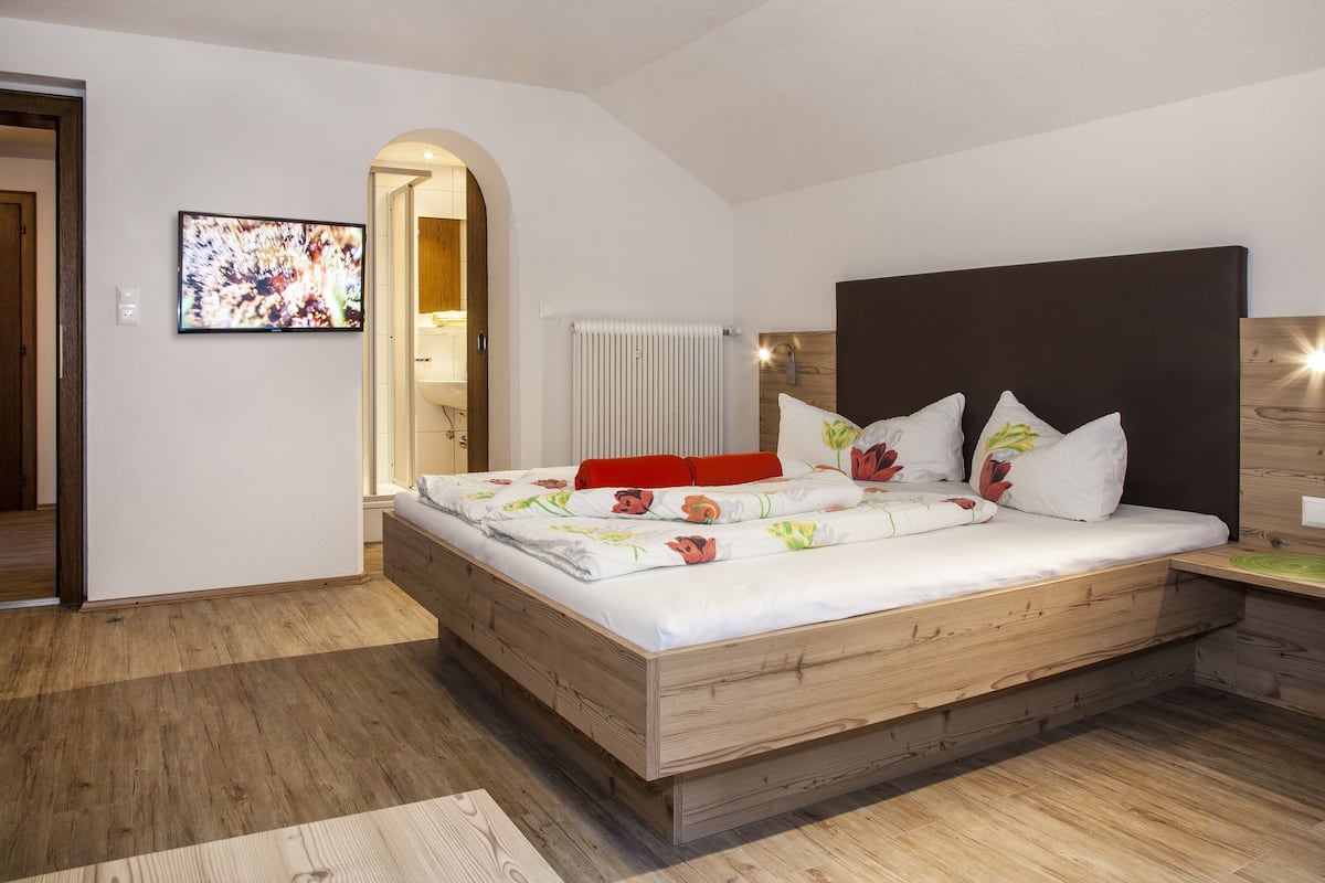 A bedroom with a wooden bed, white bedding, and a wooden headboard.