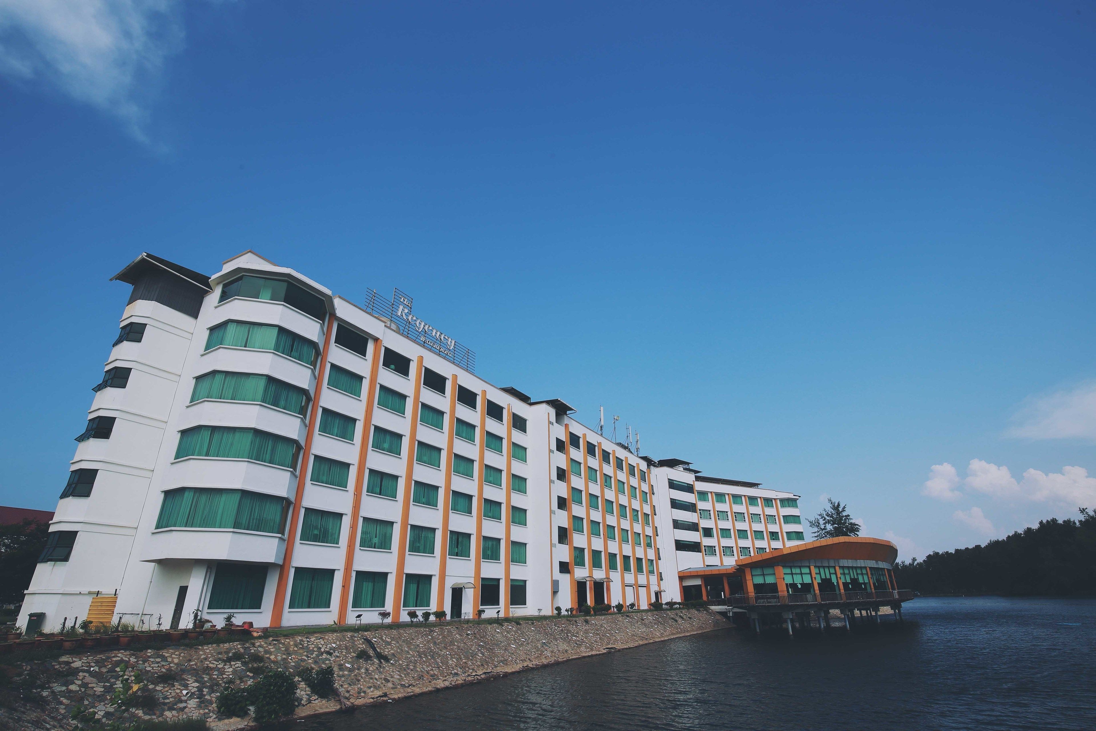 A multi-story hotel with a white facade and green accents, featuring a prominent 'Regency' sign.