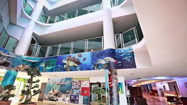 A multi-level atrium with a large aquarium display featuring marine life, potted plants, and informational posters. - The Regency Waterfront Hotel (Kuala Terengganu)