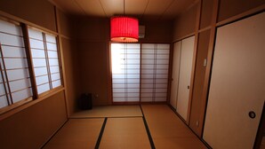 A traditional Japanese room with tatami flooring, sliding doors, and a red hanging lamp.