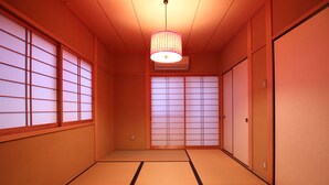A traditional Japanese room with tatami flooring, sliding doors, and a hanging light fixture.