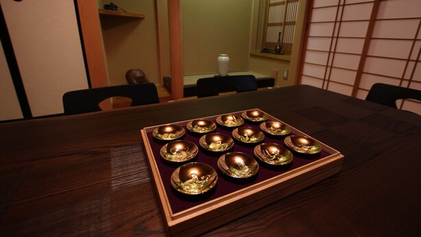 A dining table with a tray of golden bowls.
