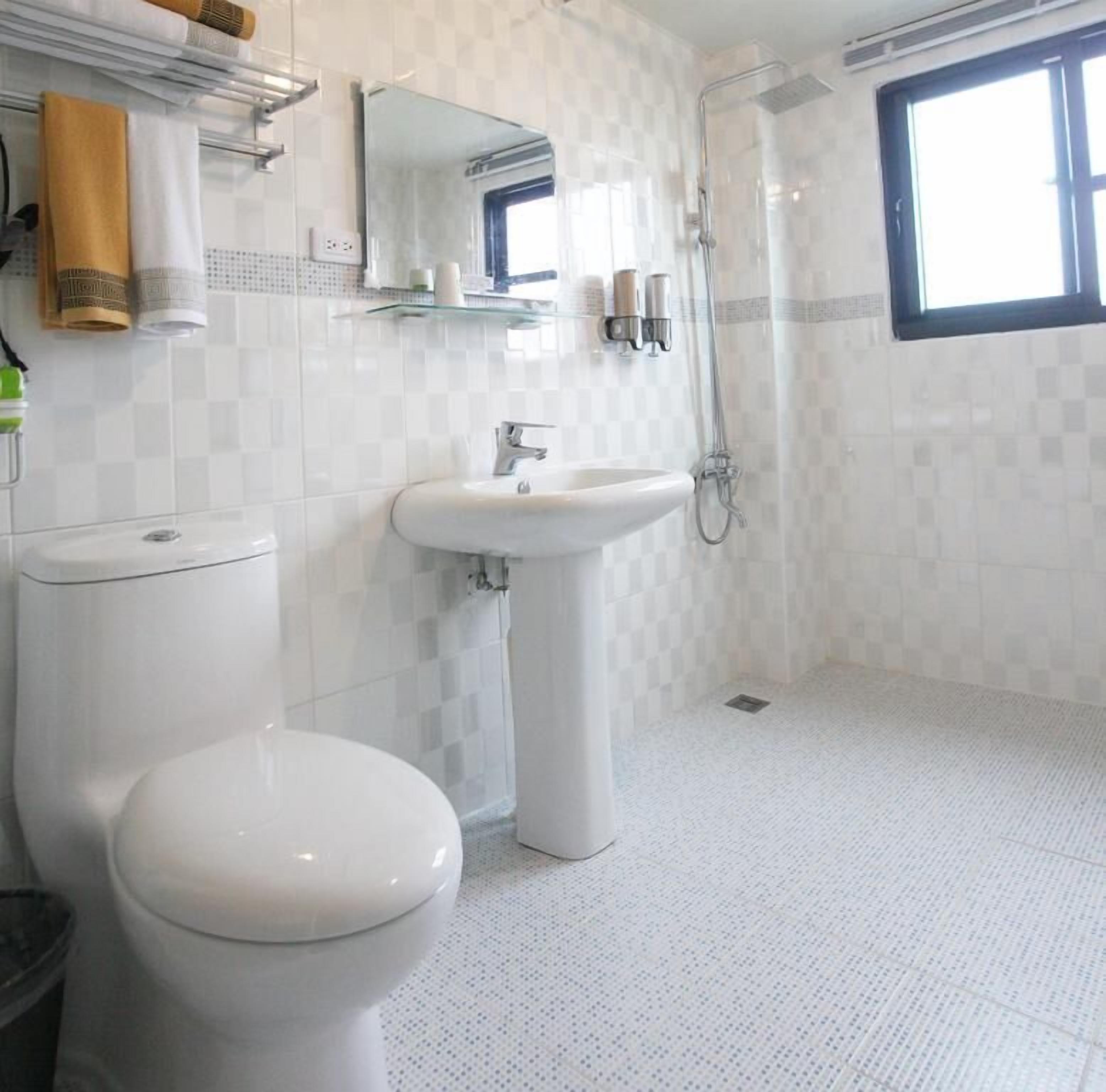 A bathroom with a toilet, sink, and shower.