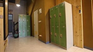 A hallway with green lockers, a staircase, and wooden walls. - Light Shadow (Budai)