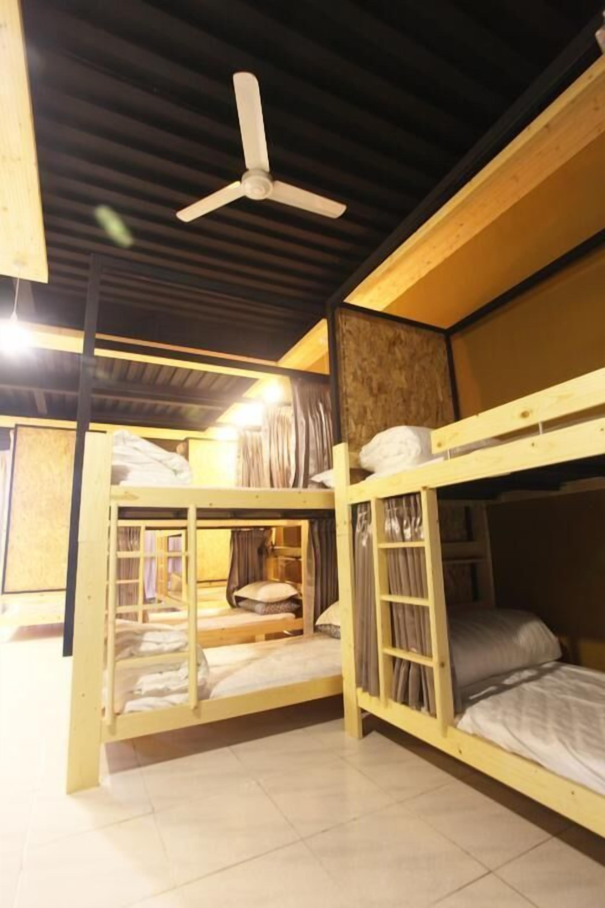 Ein Zimmer mit zwei Etagenbetten, einem Deckenventilator und einer Holzbalkendecke.