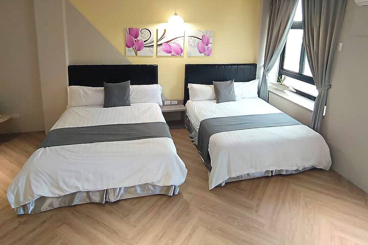 Ein Hotelzimmer mit zwei Betten, einem kleinen Tisch mit Wasserkocher und einem fenster mit Vorhängen.
