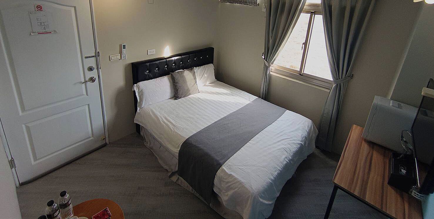 Un dormitorio con cama, escritorio, silla, ventana y puerta.