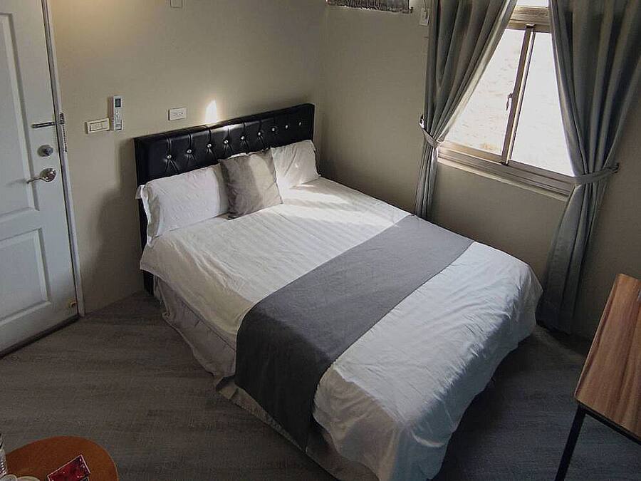 Un dormitorio con cama, escritorio, silla, ventana y puerta.