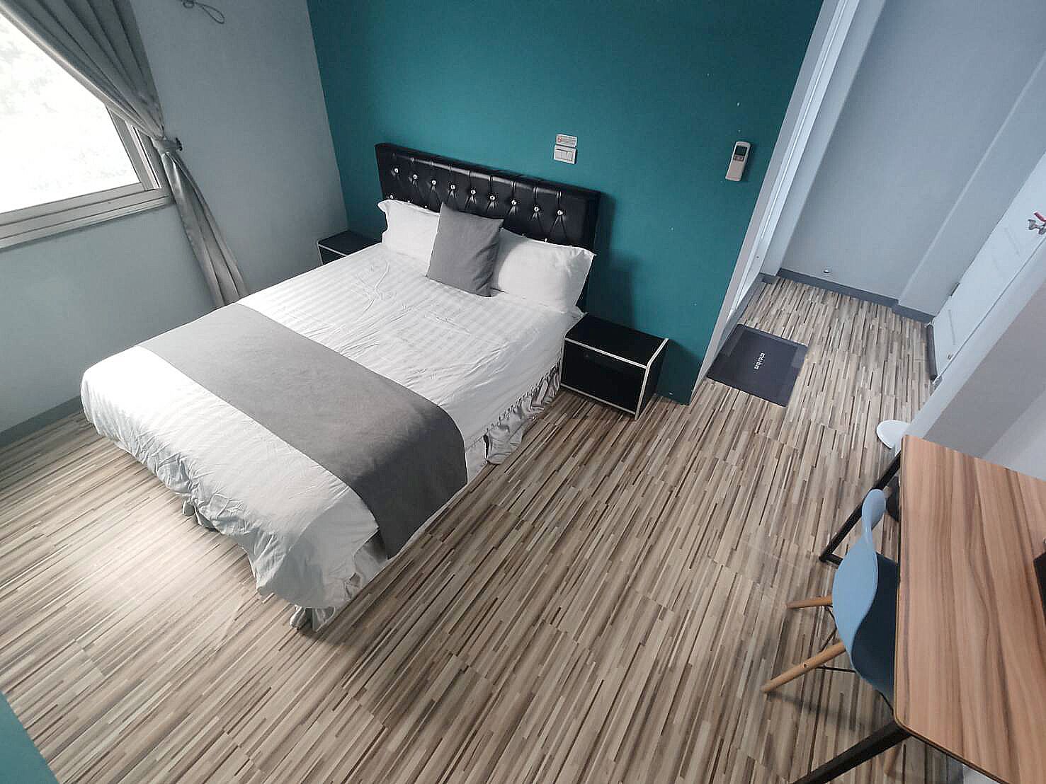 A neatly arranged bedroom with a bed, bedside tables, a desk, and a chair.