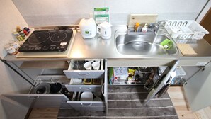 A compact kitchen with a built-in stove, sink, and storage drawers.