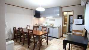 A compact kitchen with a dining table, chairs, and a refrigerator.
